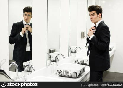 Portrait of a man getting dressed in a public restroom with mirror