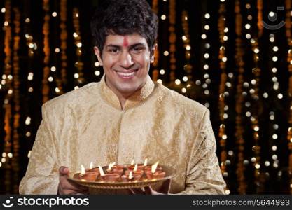 Portrait of a man holding a tray of diyas