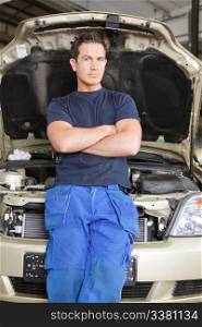 Portrait of a man mechanic leaning against a car looking at the camera