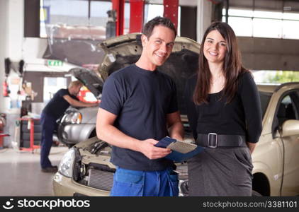 Portrait of a man mechanic with a woman customer going over the auto repair service report