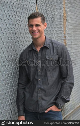 Portrait of a man standing in front of a chain link fence.