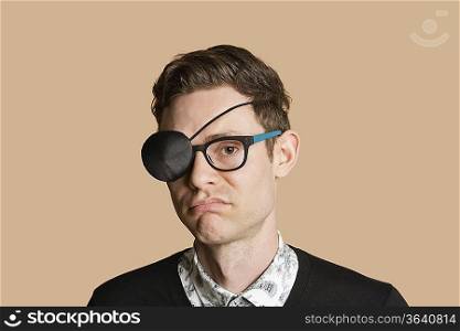 Portrait of a man wearing eye patch on glasses over colored background