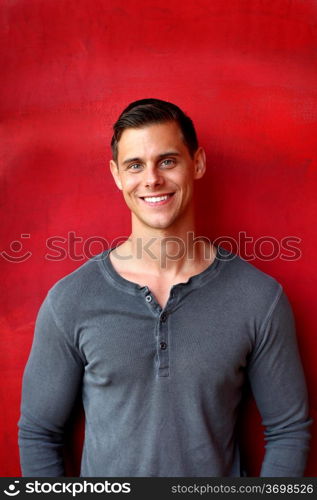 Portrait of a man with gray shirt in front red wall.