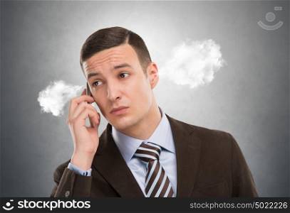 Portrait of a man with steam from his ears calling by mobile phone