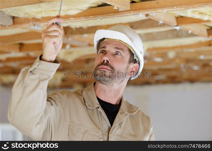 portrait of a man working on ceiling