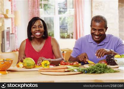 Portrait of a mature couple cutting vegetables and smiling