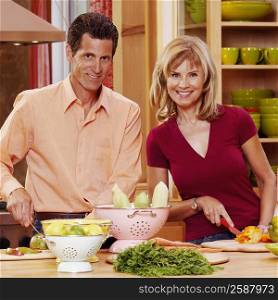 Portrait of a mature couple cutting vegetables and smiling