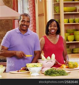 Portrait of a mature couple cutting vegetables in the kitchen and smiling