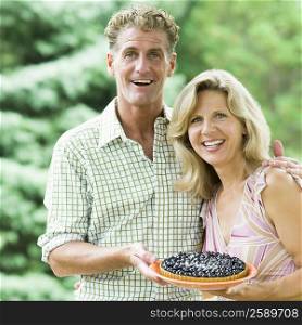 Portrait of a mature couple holding a bowl of blueberries and smiling