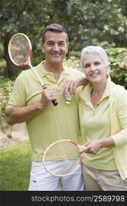 Portrait of a mature couple holding badminton rackets and smiling