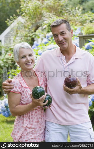 Portrait of a mature couple holding bocce balls and smiling