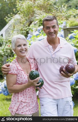 Portrait of a mature couple holding bocce balls and smiling