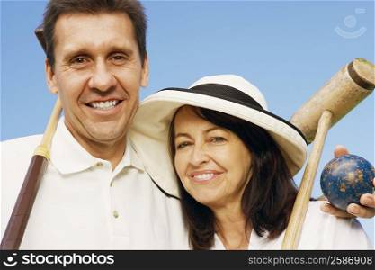 Portrait of a mature couple holding croquet mallets and a ball
