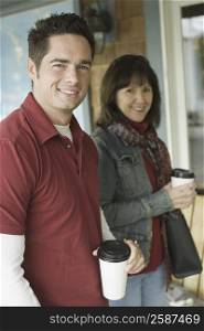 Portrait of a mature couple holding disposable cups and smiling