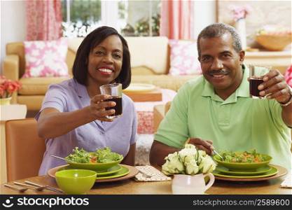 Portrait of a mature couple holding glasses of drink and smiling