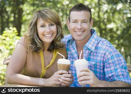 Portrait of a mature couple holding milk shakes and smiling