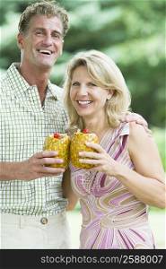 Portrait of a mature couple holding pineapples and smiling