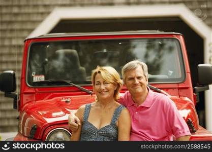 Portrait of a mature couple in front of a sports utility vehicle and smiling