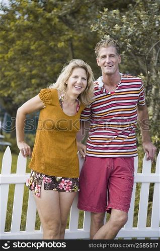Portrait of a mature couple leaning against a fence and smiling
