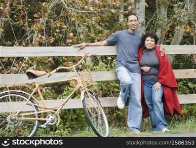 Portrait of a mature couple leaning against a fence and smiling