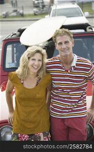 Portrait of a mature couple leaning against a jeep and smiling