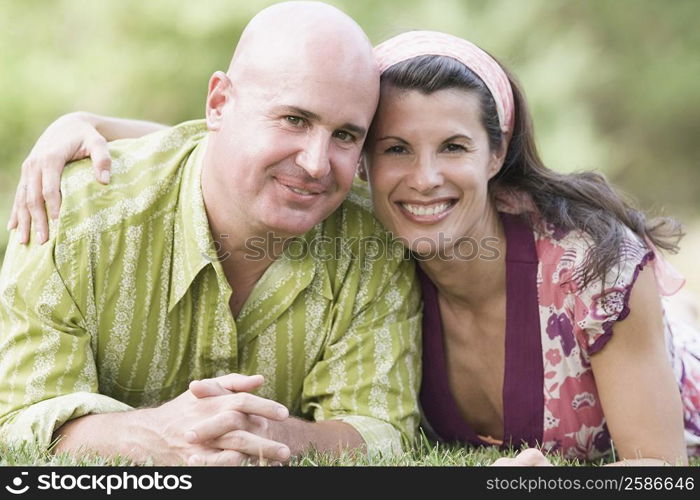 Portrait of a mature couple lying on grass and smiling