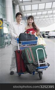 Portrait of a mature couple pushing a luggage cart