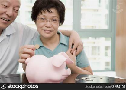 Portrait of a mature couple putting a coin in a piggy bank