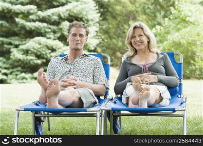 Portrait of a mature couple reclining on lounge chairs and smiling