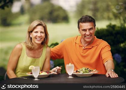 Portrait of a mature couple sitting at the table with plates of salad in front of them