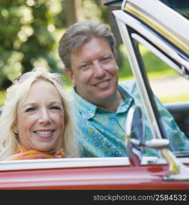 Portrait of a mature couple sitting in a convertible car and smiling