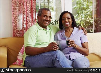 Portrait of a mature couple sitting on a couch and holding glasses of cold drink