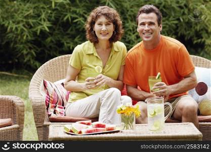 Portrait of a mature couple sitting on a couch and holding glasses of lemonade