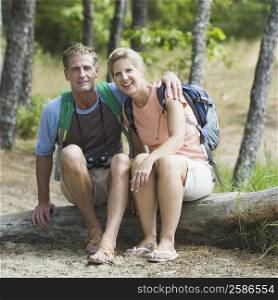 Portrait of a mature couple sitting on a tree trunk in a forest