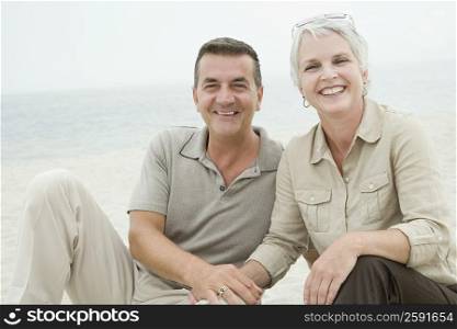 Portrait of a mature couple sitting on the beach and smiling