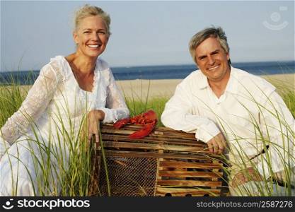 Portrait of a mature couple sitting on the beach with a lobster