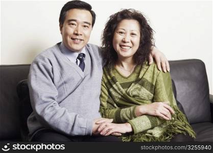 Portrait of a mature couple sitting together on a couch smiling