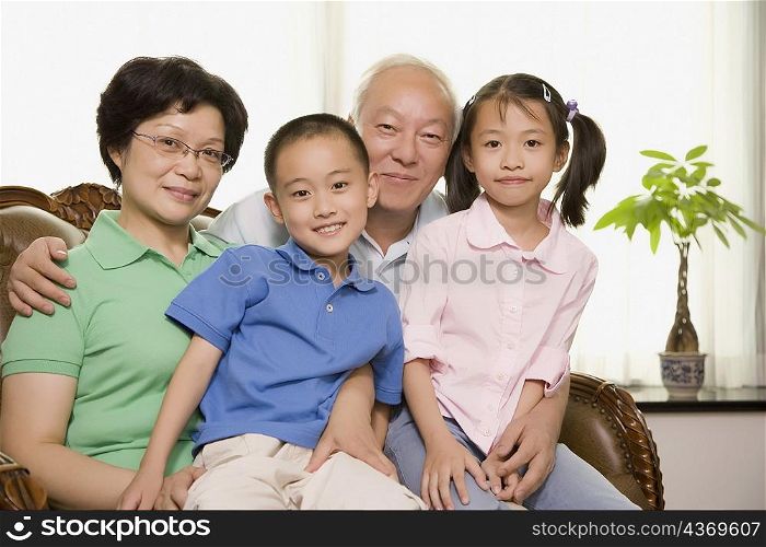 Portrait of a mature couple sitting with their grandchildren