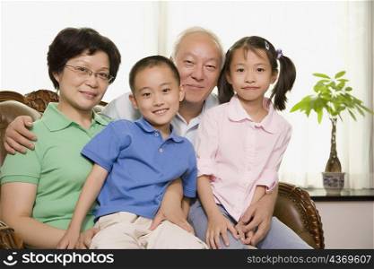 Portrait of a mature couple sitting with their grandchildren