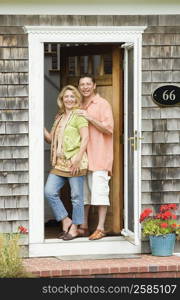 Portrait of a mature couple standing at the door of a house and smiling