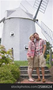 Portrait of a mature couple standing together in front of a windmill in a park