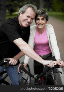 Portrait of a mature couple standing with bicycles and smiling
