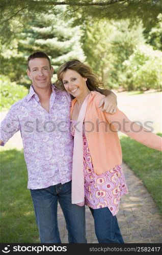 Portrait of a mature couple standing with their arm around and smiling