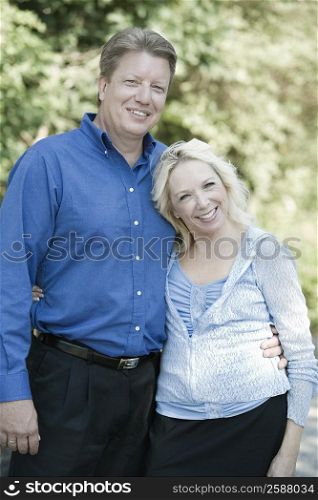 Portrait of a mature couple standing with their arm around each other and smiling