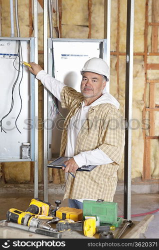 Portrait of a mature male construction worker checking electric meters at construction site