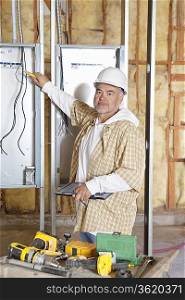 Portrait of a mature male construction worker checking electric meters at construction site