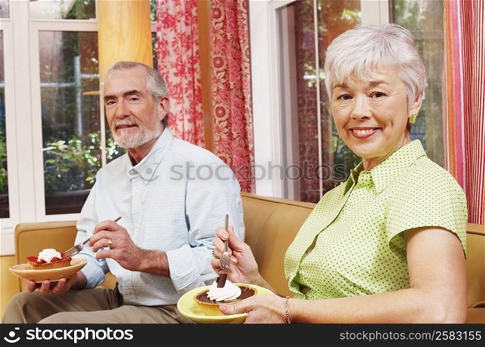 Portrait of a mature man and a senior woman eating a tart