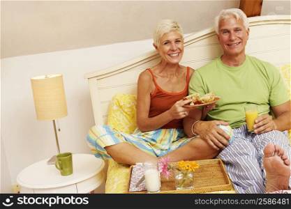 Portrait of a mature man and a senior woman having breakfast in bed