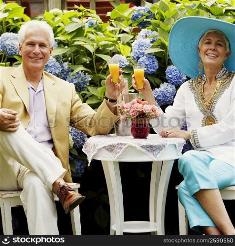 Portrait of a mature man and a senior woman sitting together and holding glasses of juice