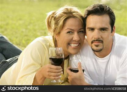 Portrait of a mature man and a young woman holding glasses of red wine